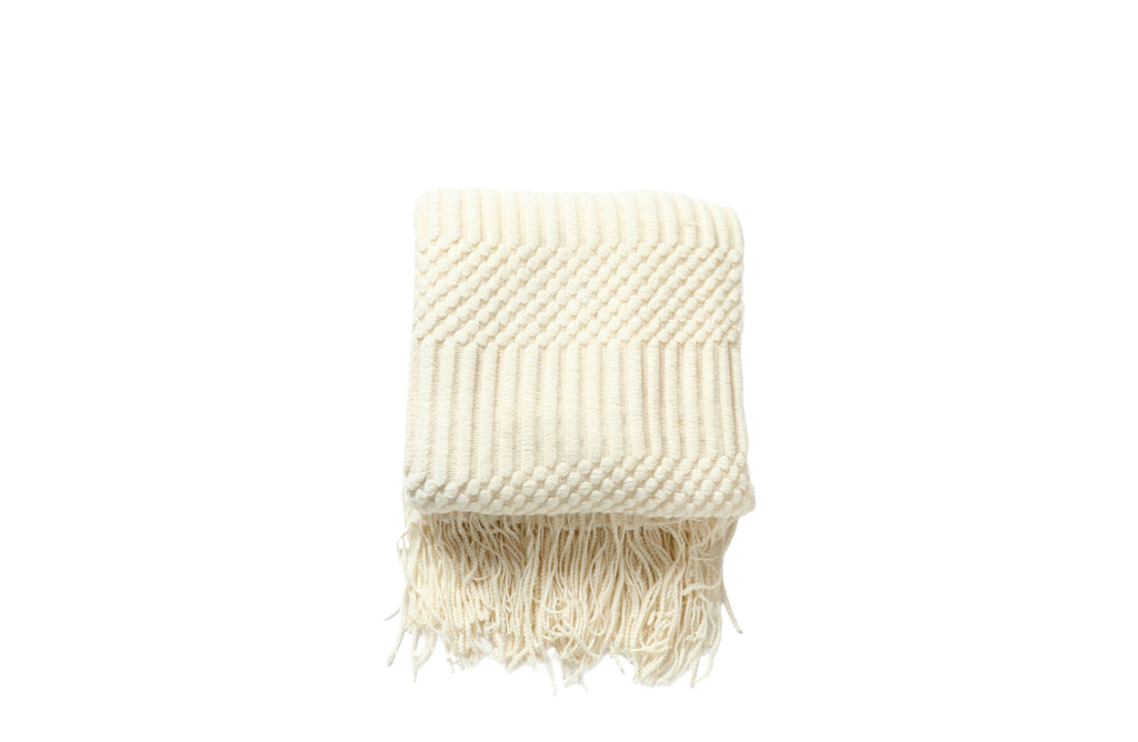 Cream Tessa throw rug blanket with a soft textured weave and fringe edges.