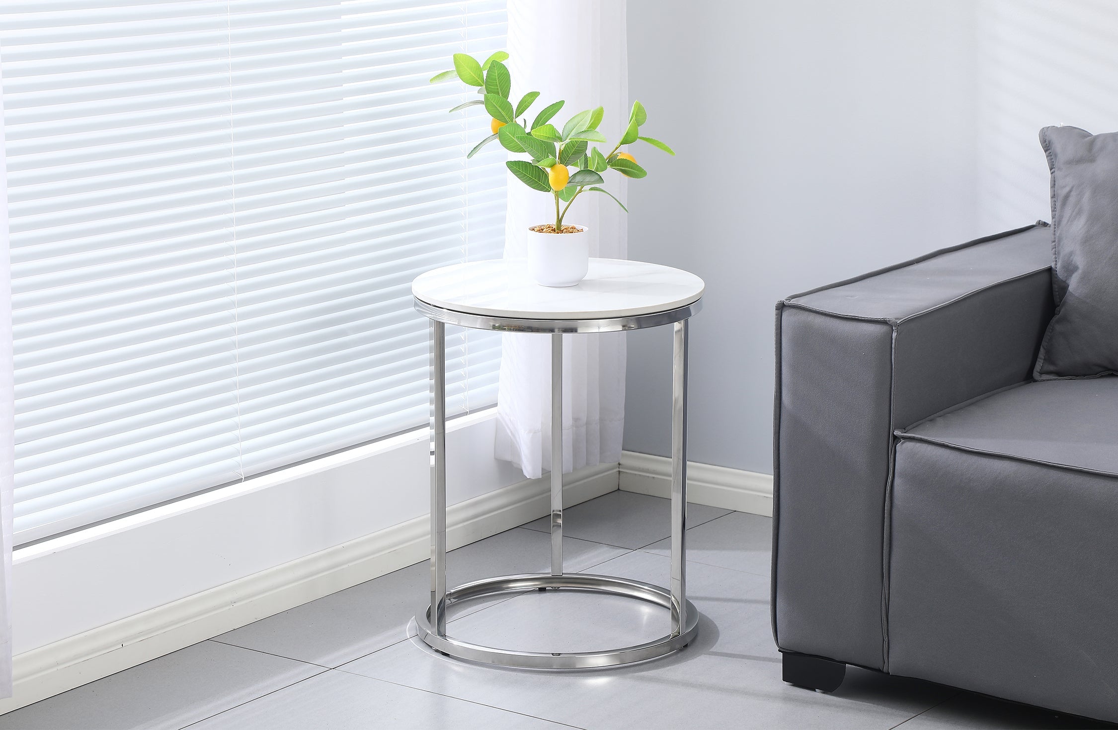 Layla side table with silver frame and marble top styled beside a contemporary sofa.